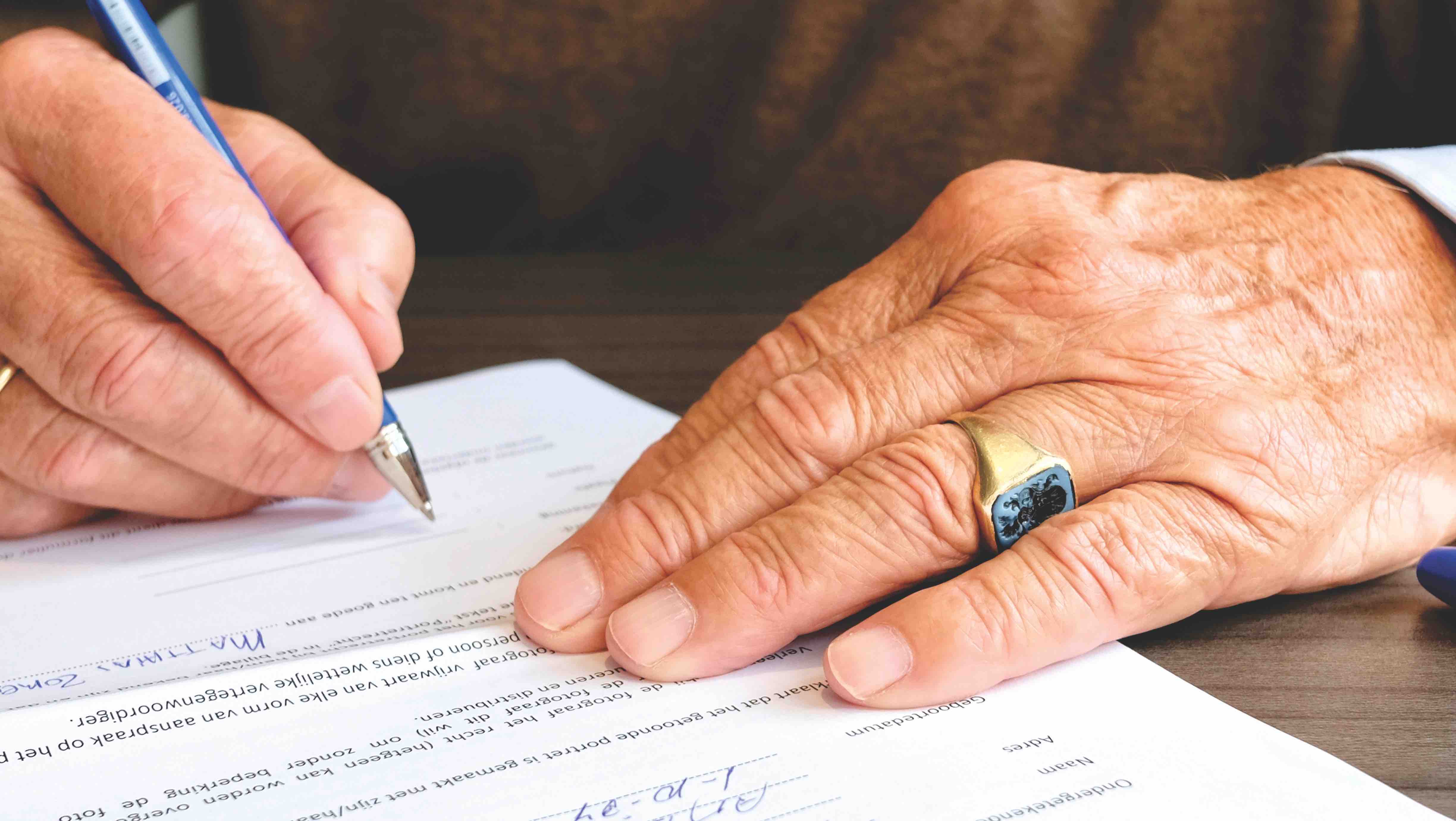 right handed person view of hands with a pen writing on a piece of paper